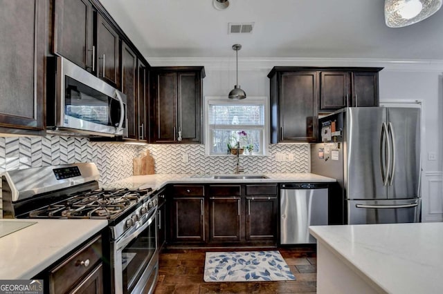 kitchen with ornamental molding, hanging light fixtures, appliances with stainless steel finishes, and dark wood-type flooring