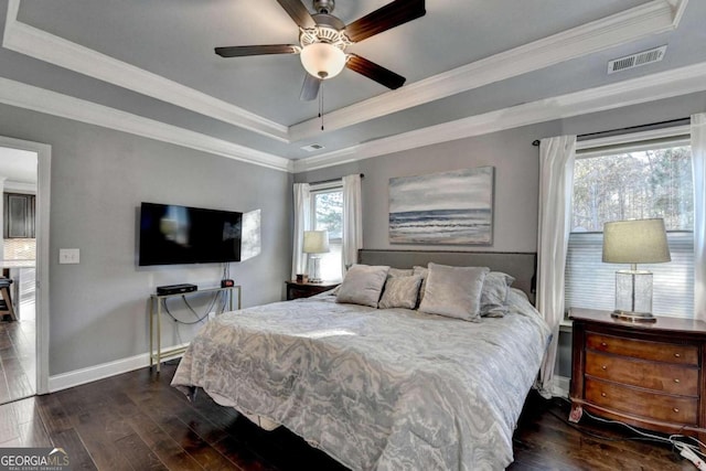 bedroom with ceiling fan, ornamental molding, dark wood-type flooring, and a tray ceiling