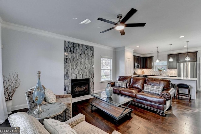 living room featuring a tile fireplace, ceiling fan, dark hardwood / wood-style floors, and ornamental molding