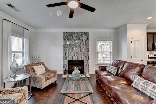 living room featuring a fireplace, dark wood-type flooring, ceiling fan, and a healthy amount of sunlight