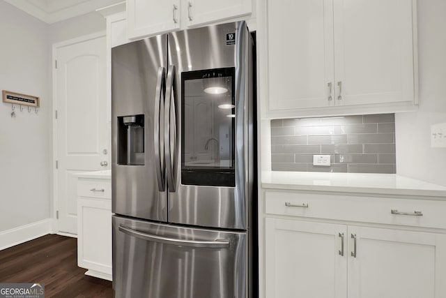 kitchen with stainless steel fridge, backsplash, crown molding, dark wood-type flooring, and white cabinets