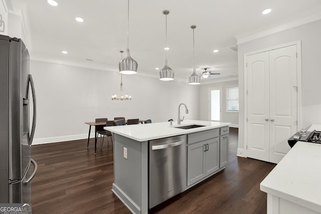 kitchen featuring ceiling fan with notable chandelier, stainless steel appliances, sink, pendant lighting, and an island with sink