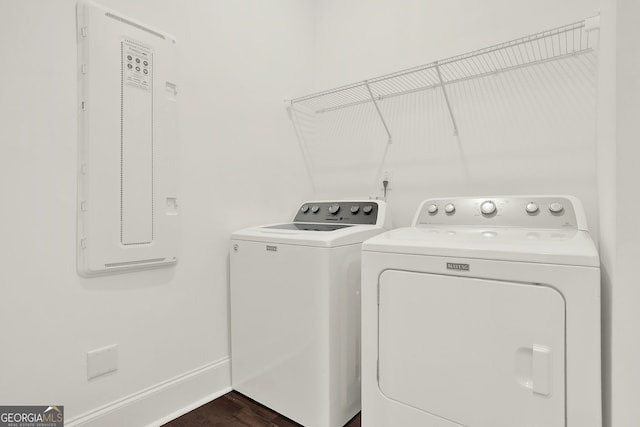 clothes washing area featuring washing machine and dryer, electric panel, and dark hardwood / wood-style floors