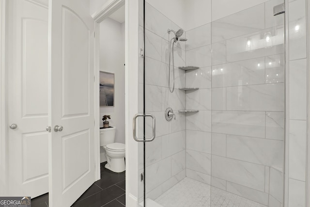 bathroom featuring tile patterned flooring, toilet, and walk in shower