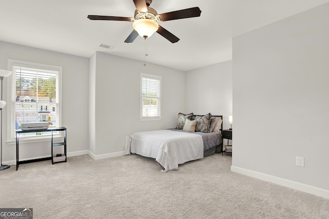 bedroom featuring multiple windows, ceiling fan, and light carpet