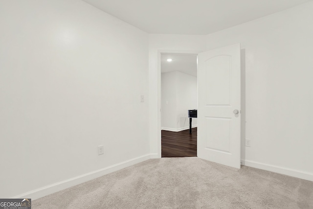 spare room with dark carpet and vaulted ceiling