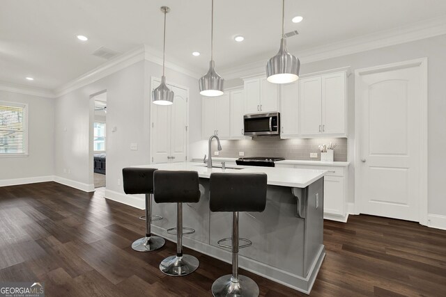 kitchen featuring decorative light fixtures, white cabinetry, a kitchen island with sink, and dark hardwood / wood-style floors