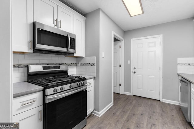 kitchen featuring decorative backsplash, white cabinetry, stainless steel appliances, and light wood-type flooring