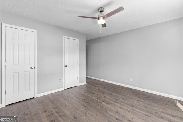 unfurnished bedroom featuring ceiling fan, dark hardwood / wood-style flooring, and a textured ceiling