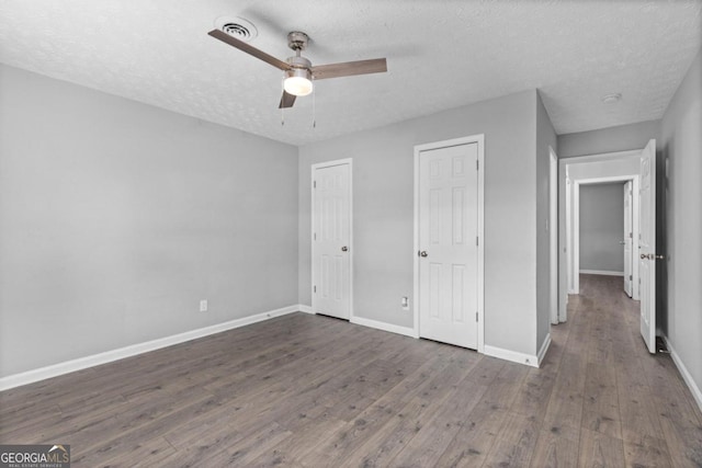 unfurnished bedroom featuring dark hardwood / wood-style floors, ceiling fan, and a textured ceiling