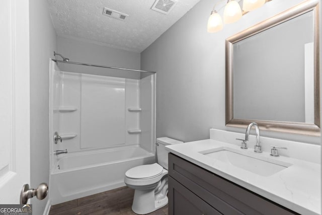 full bathroom with hardwood / wood-style floors, a textured ceiling, toilet, vanity, and shower / bathtub combination