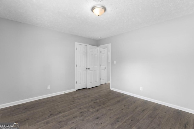 spare room featuring dark hardwood / wood-style floors and a textured ceiling