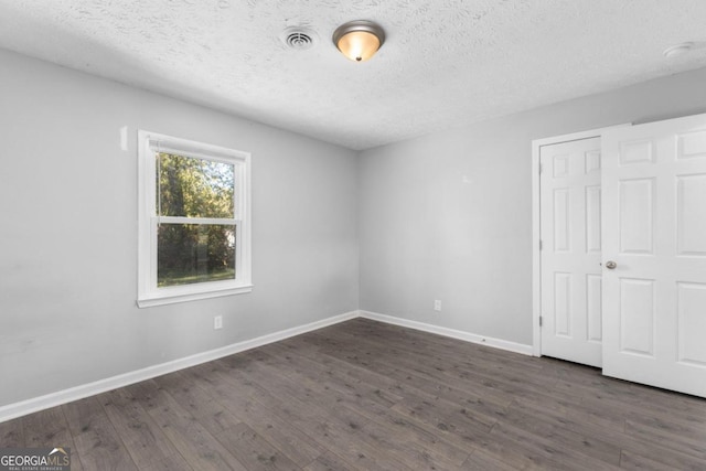 unfurnished bedroom featuring a closet, dark hardwood / wood-style flooring, and a textured ceiling