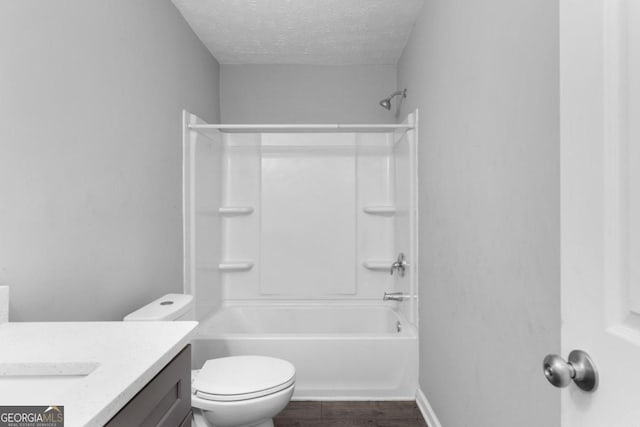 full bathroom with vanity, washtub / shower combination, hardwood / wood-style flooring, toilet, and a textured ceiling