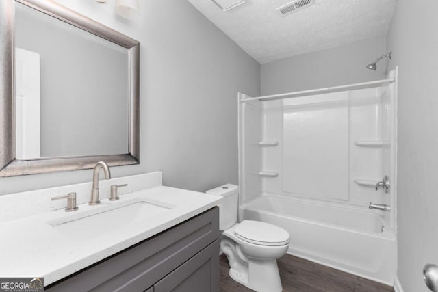 full bathroom featuring vanity, a textured ceiling, bathing tub / shower combination, wood-type flooring, and toilet