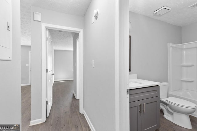 full bathroom with shower / bath combination, vanity, a textured ceiling, wood-type flooring, and toilet