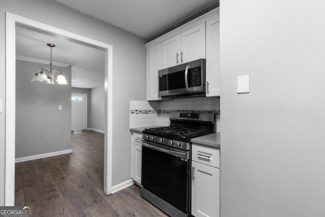 kitchen with dark wood-type flooring, white cabinets, decorative backsplash, appliances with stainless steel finishes, and a chandelier