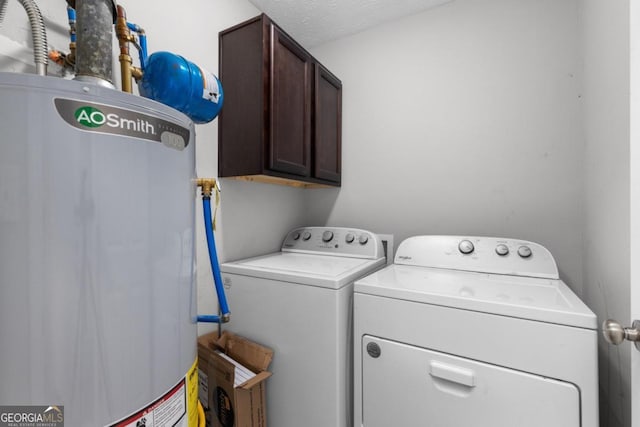 clothes washing area featuring cabinets, a textured ceiling, gas water heater, and washer and clothes dryer