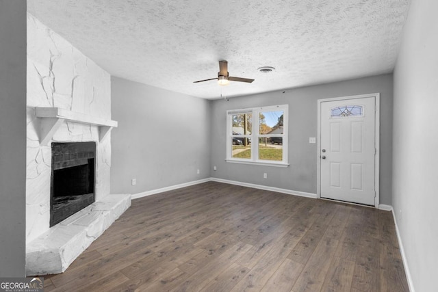 unfurnished living room with a textured ceiling, ceiling fan, a fireplace, and dark hardwood / wood-style floors