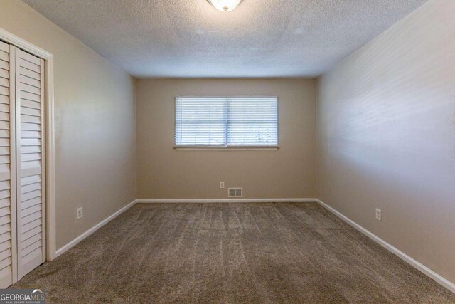 empty room featuring dark colored carpet and a textured ceiling