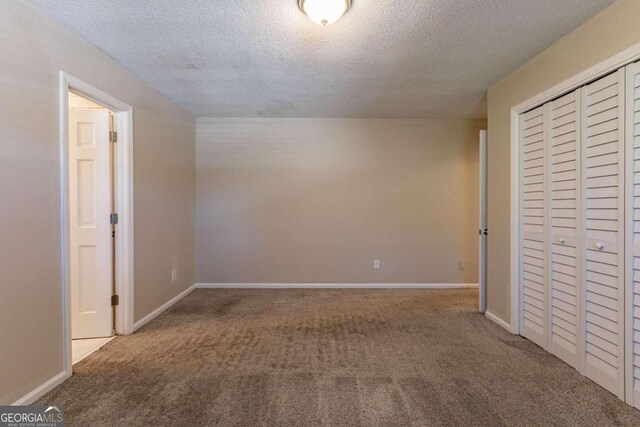 unfurnished bedroom with carpet flooring, a closet, and a textured ceiling