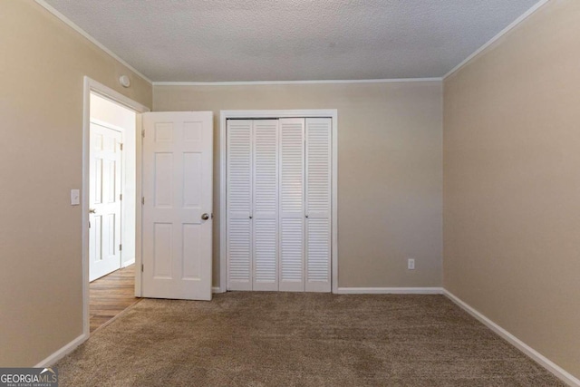 unfurnished bedroom featuring a closet, carpet, a textured ceiling, and ornamental molding