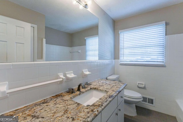 bathroom with vanity, tile patterned floors, toilet, tile walls, and walk in shower