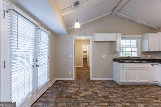 3619 Colonial Trl, Douglasville, GA 30135 - kitchen with white cabinets, vaulted ceiling with beams, plenty of natural light, and sink