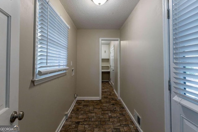 hall featuring plenty of natural light and a textured ceiling