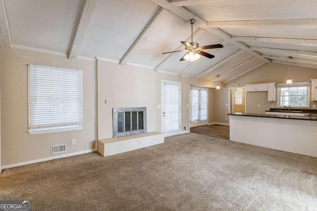 unfurnished living room featuring lofted ceiling with beams, sink, a brick fireplace, ceiling fan, and carpet floors