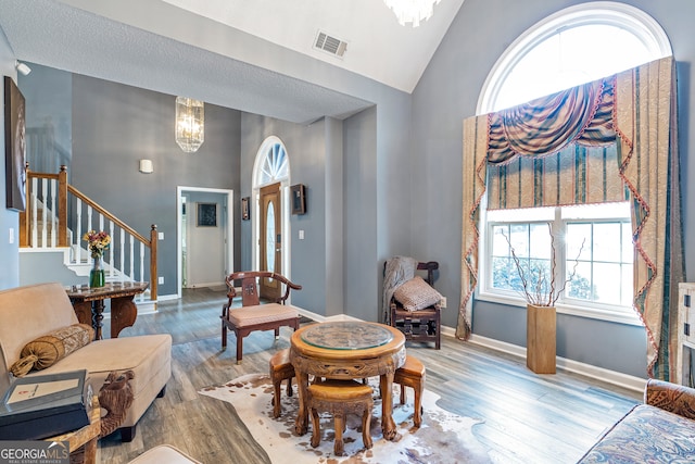 living room featuring a chandelier, a textured ceiling, vaulted ceiling, and light hardwood / wood-style flooring