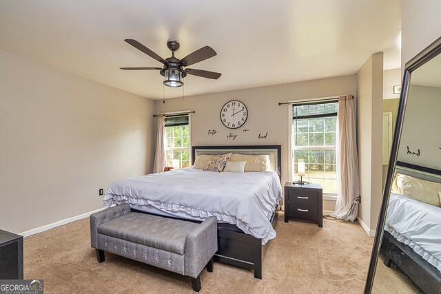 bedroom with light colored carpet, multiple windows, and ceiling fan