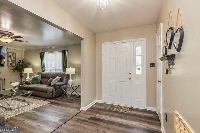 entryway featuring plenty of natural light, crown molding, dark wood-type flooring, and ceiling fan with notable chandelier