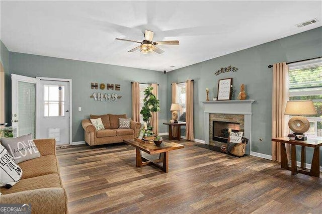 living room with dark hardwood / wood-style floors, ceiling fan, and a stone fireplace