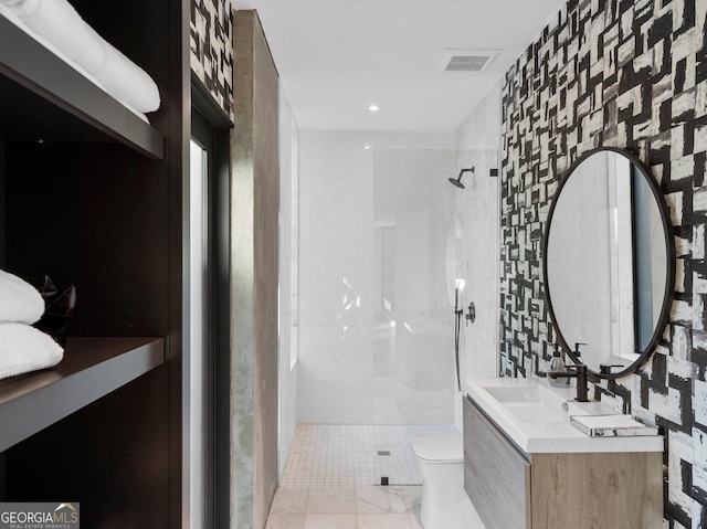 bathroom featuring a tile shower, vanity, tile walls, and toilet