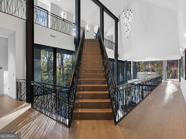 stairway featuring wood-type flooring and high vaulted ceiling