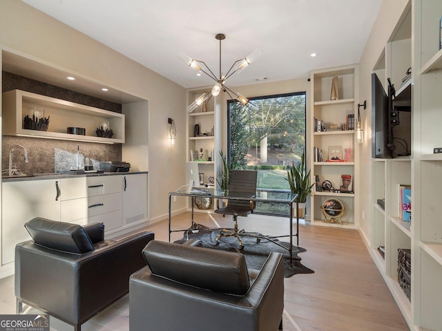 living room featuring a chandelier, light hardwood / wood-style flooring, built in features, and sink