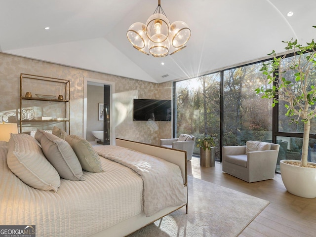 bedroom featuring hardwood / wood-style floors, vaulted ceiling, ensuite bath, and a notable chandelier