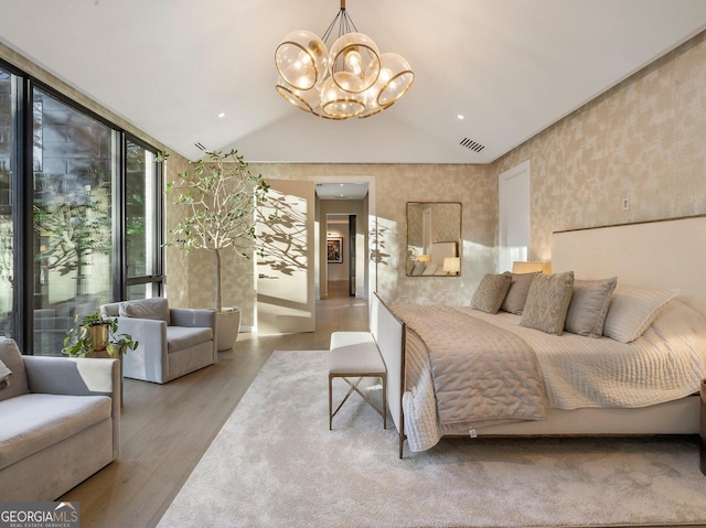 bedroom featuring light wood-type flooring, vaulted ceiling, a wall of windows, and a notable chandelier