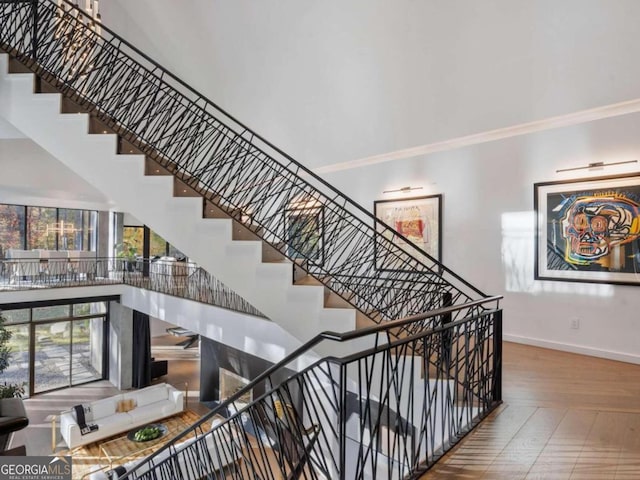 stairway with a towering ceiling and hardwood / wood-style flooring