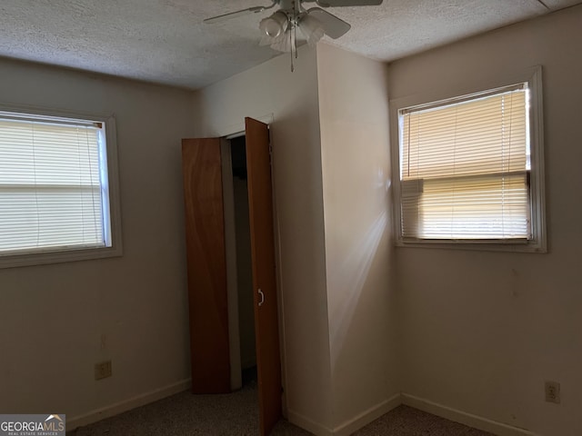 interior space with ceiling fan, a healthy amount of sunlight, and a textured ceiling