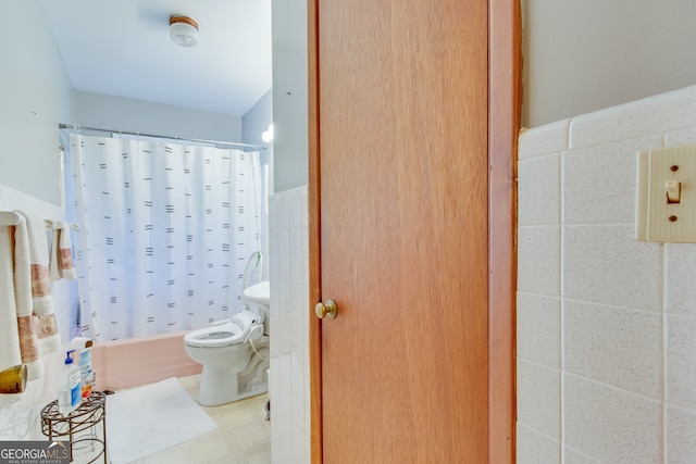 bathroom with shower / bath combo, toilet, and tile walls