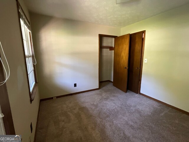 unfurnished bedroom featuring a textured ceiling and carpet