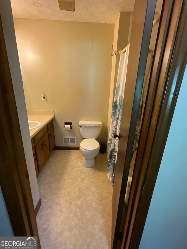 bathroom with toilet, a textured ceiling, and vanity