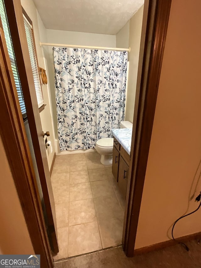 full bathroom with toilet, tile patterned floors, vanity, and shower / tub combo with curtain