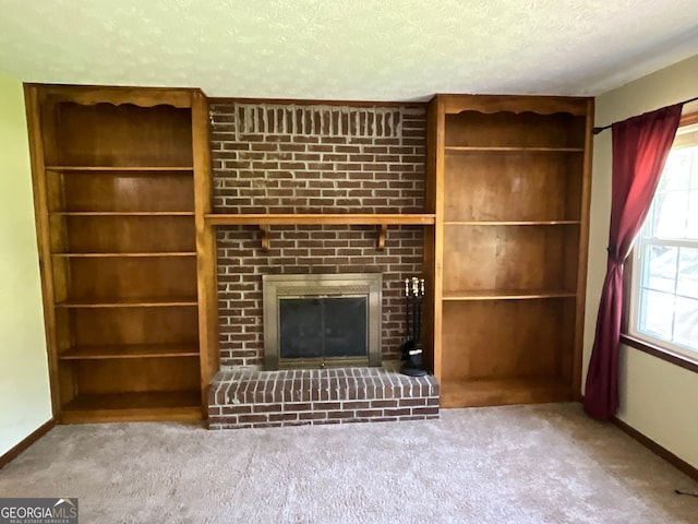 unfurnished living room featuring built in features, carpet flooring, a textured ceiling, and a brick fireplace