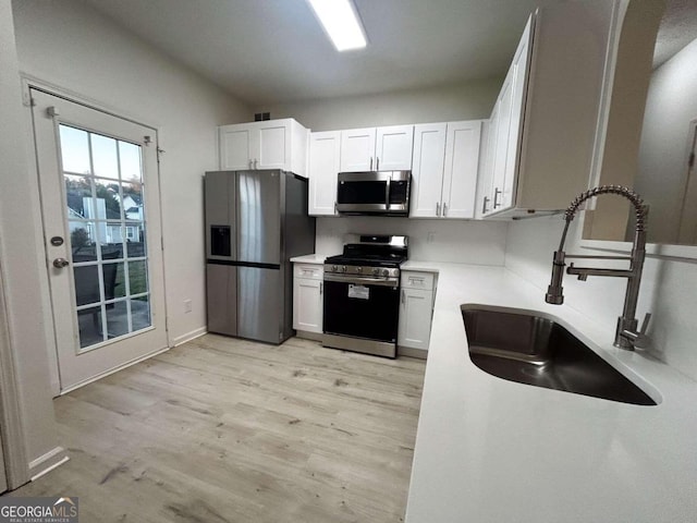 kitchen with white cabinetry, sink, appliances with stainless steel finishes, and light hardwood / wood-style flooring