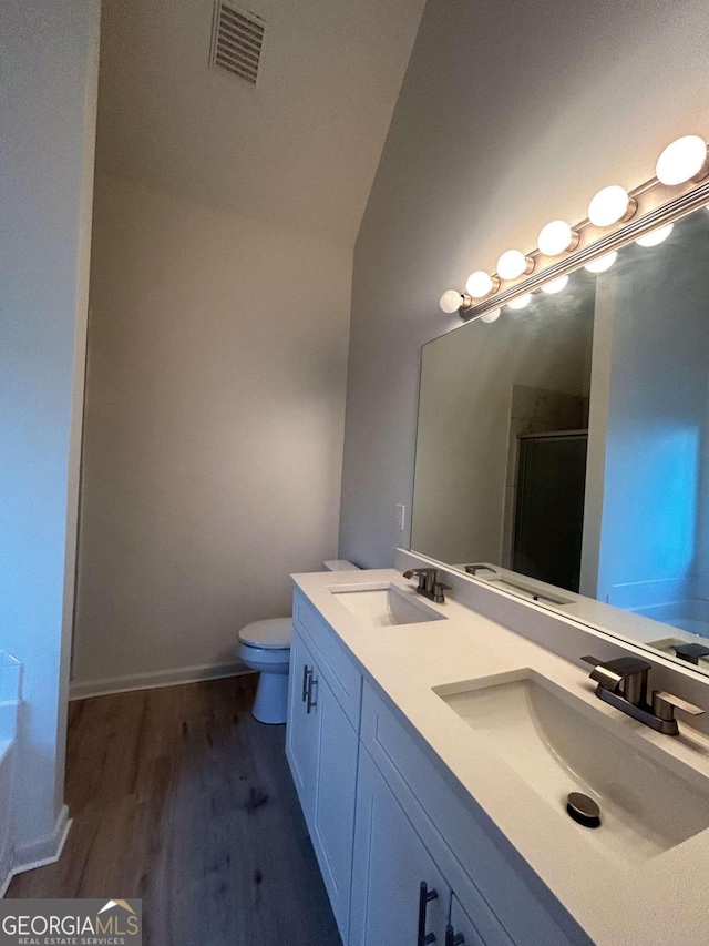 bathroom featuring vanity, a shower with door, hardwood / wood-style floors, toilet, and lofted ceiling