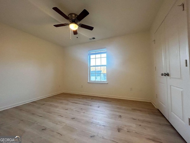 empty room with ceiling fan and light hardwood / wood-style flooring