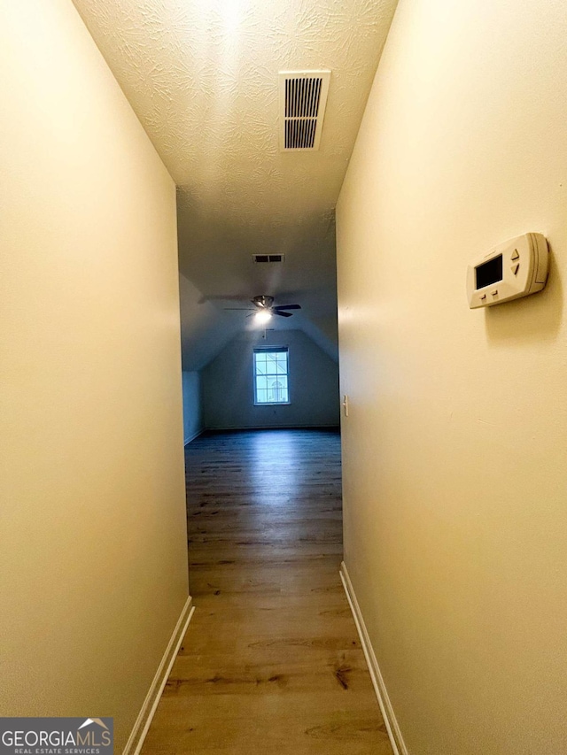 hallway featuring a textured ceiling, lofted ceiling, and hardwood / wood-style flooring